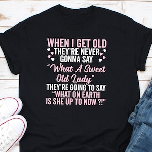 Puede incluir: Camiseta negra con texto rosa que dice "WHEN I GET OLD THEY'RE NEVER GONNA SAY "What A Sweet Old Lady" THEY'RE GOING TO SAY "WHAT ON EARTH IS SHE UP TO NOW?!"