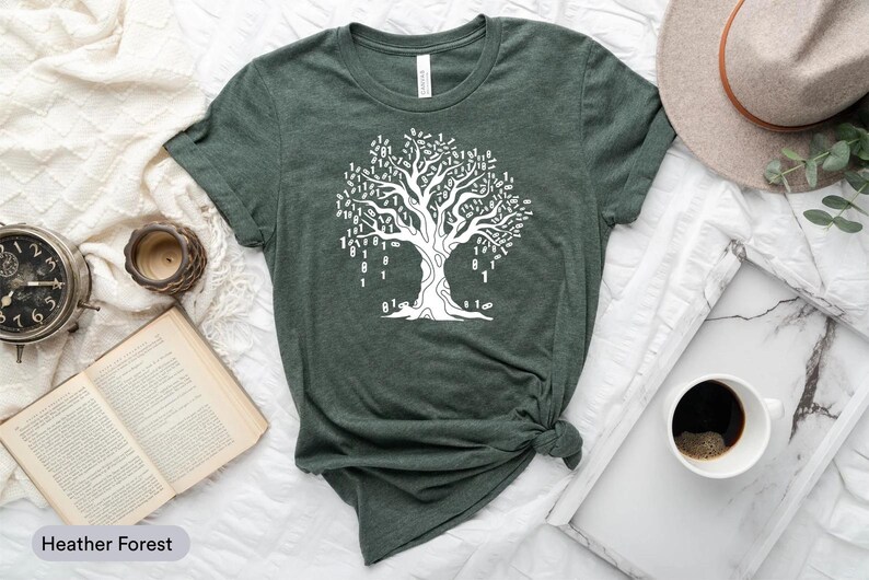 a green t-shirt with a white tree graphic, a hat, a book, a cup of coffee, and a clock, all arranged on a white surface.