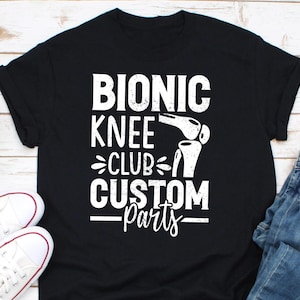 May include: Black t-shirt with white text that reads "Bionic Knee Club Custom Parts" and a graphic of a knee joint.