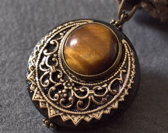May include: A round pendant with a gold-toned metal frame and intricate design. The pendant features a large, round tiger's eye gemstone in the center.