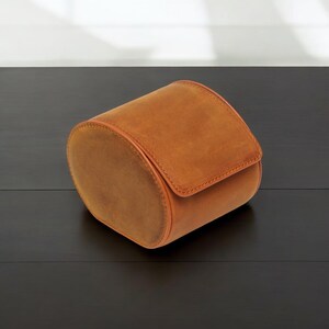 May include: A brown leather watch roll for storing and protecting watches.