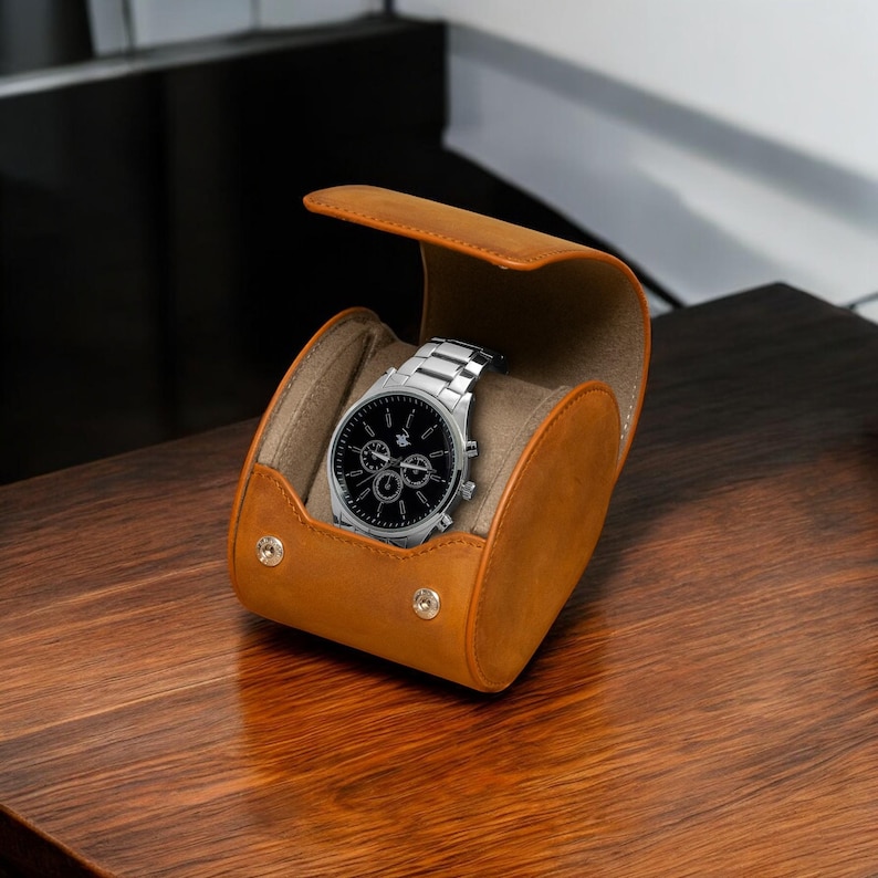 May include: A brown leather watch roll with a silver watch inside. The watch has a black face with silver hands and a chronograph.
