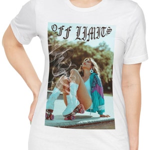 May include: White t-shirt with a graphic print of a woman in a white and blue outfit on roller skates. The text "OFF LIMITS" is printed in black above the graphic.