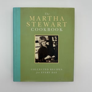 Puede incluir: Un libro de cocina de tapa dura titulado "The Martha Stewart Cookbook" con una cubierta verde y una foto de Martha Stewart. El t&iacute;tulo del libro est&aacute; en letras doradas, y el subt&iacute;tulo dice "Collected Recipes for Every Day."