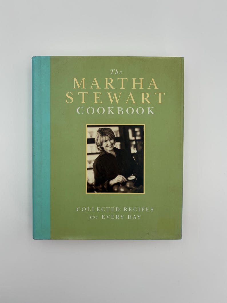 Puede incluir: Un libro de cocina de tapa dura titulado "The Martha Stewart Cookbook" con una cubierta verde y una foto de Martha Stewart. El t&iacute;tulo del libro est&aacute; en letras doradas, y el subt&iacute;tulo dice "Collected Recipes for Every Day."