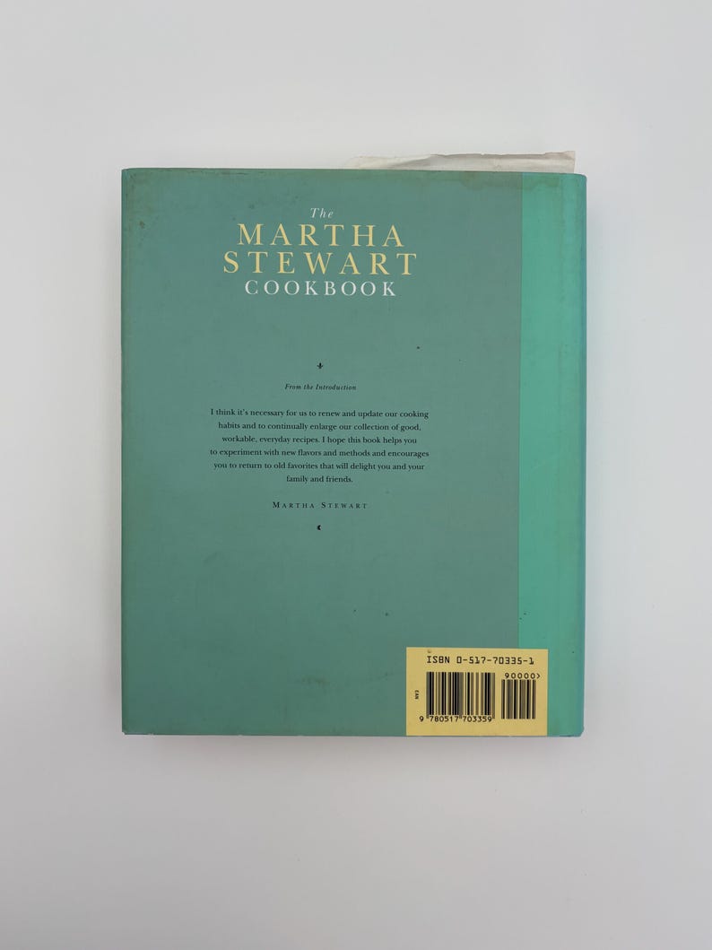 Puede incluir: La contraportada turquesa de "The Martha Stewart Cookbook" con texto blanco. El t&iacute;tulo est&aacute; en la parte superior, con una introducci&oacute;n debajo. El ISBN est&aacute; en una etiqueta amarilla. Un libro de cocina cl&aacute;sico.