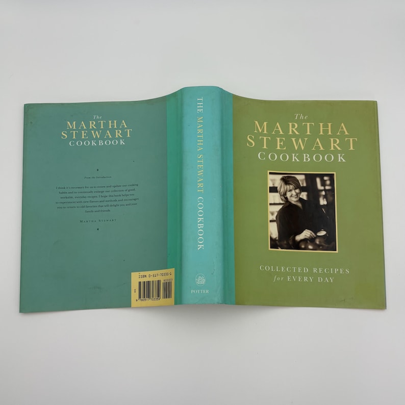 Puede incluir: Un libro de cocina abierto con una cubierta turquesa y verde. El t&iacute;tulo "The Martha Stewart Cookbook" se muestra en letras doradas. El lado derecho presenta una foto de Martha Stewart y el subt&iacute;tulo "Collected Recipes for Every Day."