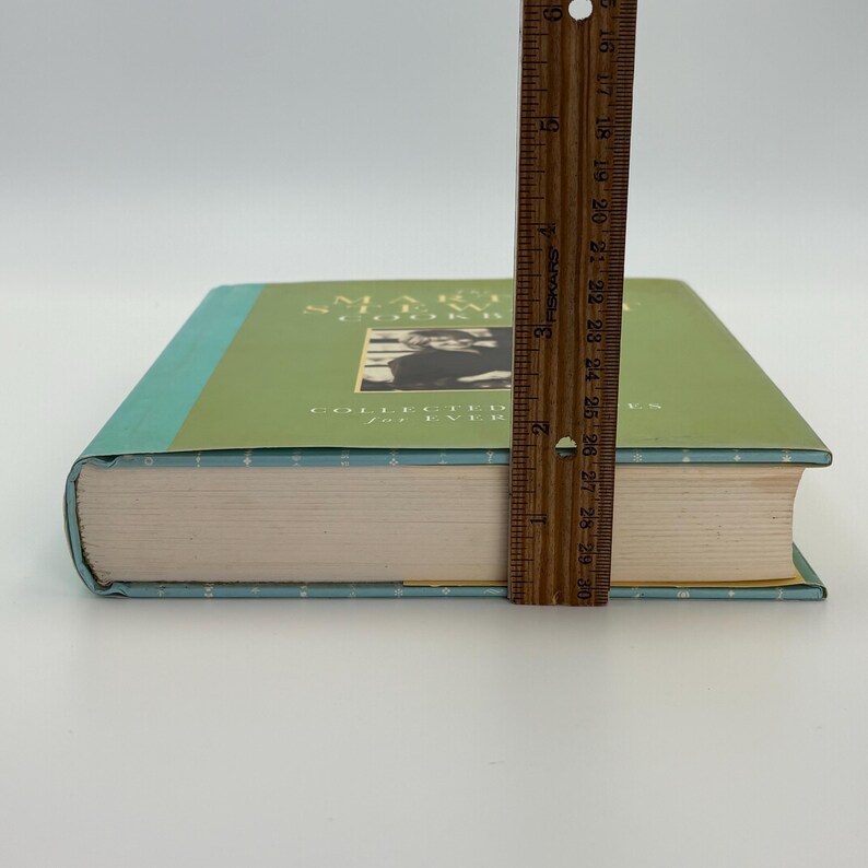 Puede incluir: Un libro de tapa dura con una cubierta verde y una foto de una persona. El libro se mide con una regla, mostrando un grosor de aproximadamente 3,8 cm. El t&iacute;tulo del libro es visible, con las palabras "Collected for Ever".