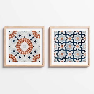 May include: Two framed prints featuring geometric patterns. The print on the left has a white background with a red, blue and white circular pattern. The print on the right has a white background with a blue, red and white geometric pattern.