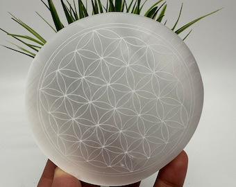 Op de afbeelding: Witte seleniet laadplaat met een gegraveerd levensbloem ontwerp.