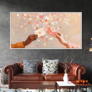 May include: A framed artwork depicts two hands exchanging envelopes against a backdrop of floating hearts. The color palette includes soft pinks, peaches, and creams, creating a romantic and warm ambiance. The artwork is displayed above a brown leather sofa.