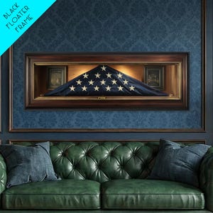 May include: A rectangular wooden display case with a dark finish containing a folded American flag with white stars on a blue field. The case features a black floater frame design and is mounted on a wall above a green tufted leather sofa.