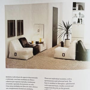 Pu&ograve; includere: Una pagina di rivista di interior design con sedute modulari e un tavolo in fibra di vetro. Le sedute sono rivestite in bianco e nero, con un dettaglio di fibbia rettangolare. Il testo "MP-75 1972" &egrave; visibile in alto a sinistra.