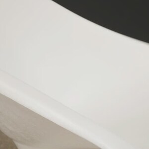 May include: A white, modern bathtub with a curved design. The tub has a smooth, glossy finish and a minimalist aesthetic. The image shows a close-up of the tub's interior and exterior.