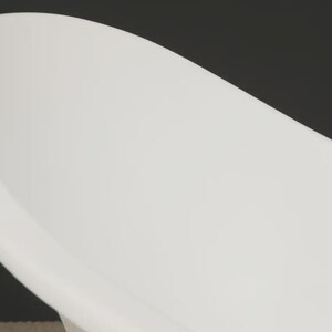 May include: A close-up of a white, oval-shaped bathtub. The tub has a smooth, curved design and is set against a dark background. The image highlights the clean lines and modern aesthetic of the bathroom fixture.