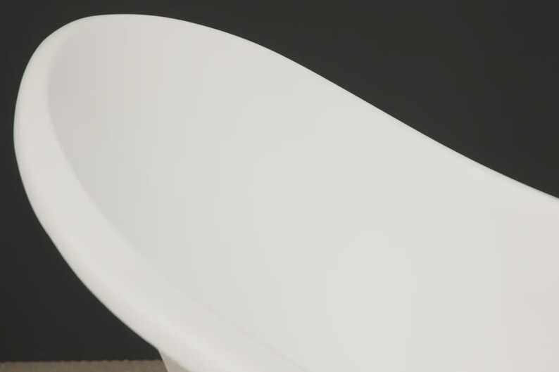 May include: A close-up of a white, oval-shaped bathtub. The tub has a smooth, curved design and is set against a dark background. The image highlights the clean lines and modern aesthetic of the bathroom fixture.