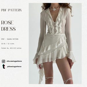 Op de afbeelding: Een witte jurk met lange mouwen, een gerimpeld lijfje en een gelaagde rok. De jurk heeft een V-hals en een asymmetrische zoom. De afbeelding bevat tekst: "PDF PATTERN ROSE DRESS" en social media handles voor naaipatronen.