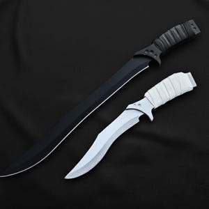 May include: Two knives on a black background. One is a long, black blade with a textured black handle. The other is a smaller, curved blade with a white handle wrapped in white material. The blades are sharp and the overall aesthetic is sleek.