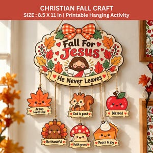Puede incluir: Un letrero colgante de 21,59 por 27,94 cm con el texto Fall For Jesus He Never Leaves. Presenta una ilustración central de Jesús rodeada de hojas de otoño y un lazo, con seis figuras colgantes: una hoja, una ardilla, una manzana, un pavo, un hongo y una porción de tarta.