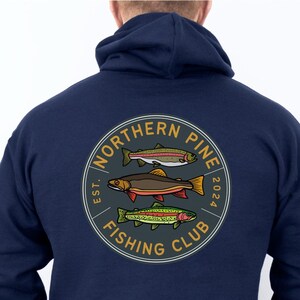 May include: A navy blue hooded sweatshirt with a circular logo on the back. The logo features three trout fish and the text "Northern Pine Fishing Club Est. 2024".