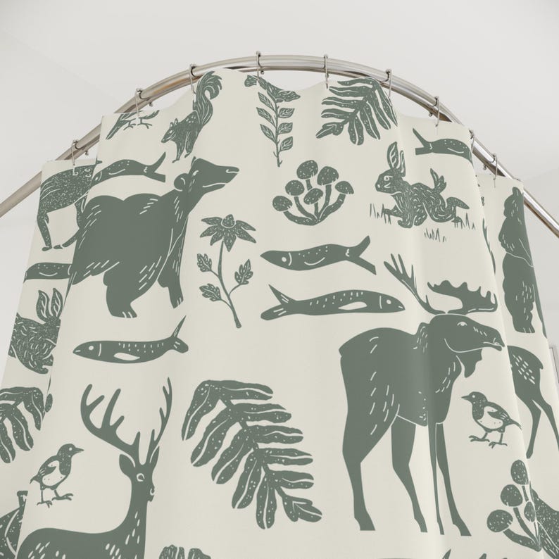 A shower curtain with a repeating pattern of forest animals in dark green on a cream background. The woodland design includes bears, deer, rabbits, foxes, birds, fish, and plants. The curtain has a whimsical log cabin aesthetic.
