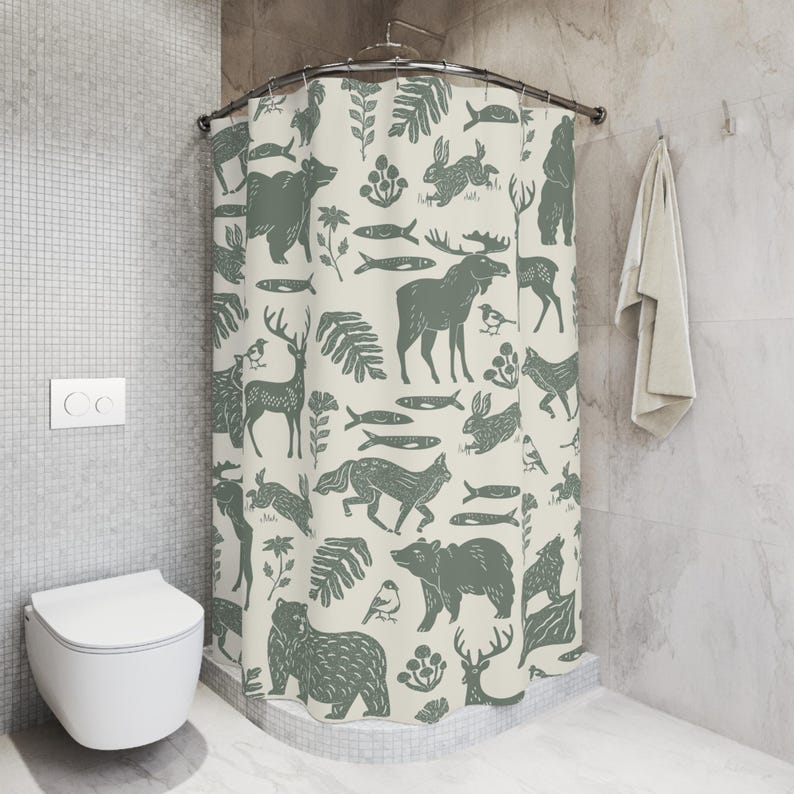 A shower curtain with a repeating pattern of forest animals in dark green on a cream background. The woodland design includes bears, deer, rabbits, foxes, birds, fish, and plants. The curtain has a whimsical log cabin aesthetic.