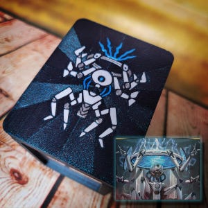 May include: A black and blue card featuring a white robot design. The robot has a circular head and multiple limbs. The card is on a wooden surface. A smaller image of the robot is in the bottom right corner.