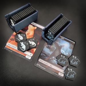 May include: Two blue card holders filled with black game pieces, alongside game cards and black and white tokens. The cards read "Mouse" and "Rat" with "1/1" tokens. The tokens have a white rat design.