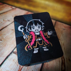 May include: A set of three ceramic mugs with a speckled, matte finish. The mugs are in shades of cream, light gray, and dark gray. Each mug has a simple, minimalist design and a rounded handle. The mugs are likely for coffee or tea.