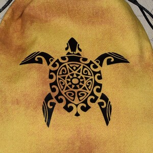 May include: A yellow fabric dice bag with a black turtle design. The bag has a drawstring closure and is made of a soft, textured fabric. The bag is surrounded by a variety of colorful dice.