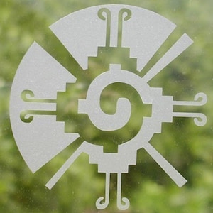 May include: White etched design of a stylized sun with a spiral in the center. The design is reminiscent of Aztec or Mayan art.