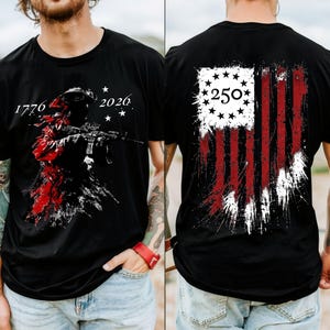 May include: A black t-shirt featuring a graphic on the front and back. The front displays a silhouette of a soldier with a rifle, the text 1776 and 2026, and stars. The back shows a distressed American flag design with the number 250 inside a circle.