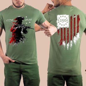 May include: An olive green t-shirt featuring a graphic on the front of a soldier in a tricorn hat holding a rifle with the text 1776 and 2026. The back displays a distressed American flag design with a circle of stars and the number 250.