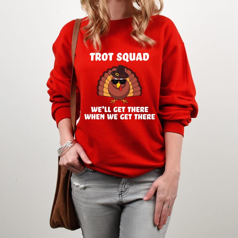 May include: A red sweatshirt featuring the words "TROT SQUAD" and a cartoon turkey wearing sunglasses and a pilgrim hat. The text "WE'LL GET THERE WHEN WE GET THERE" is below the turkey.