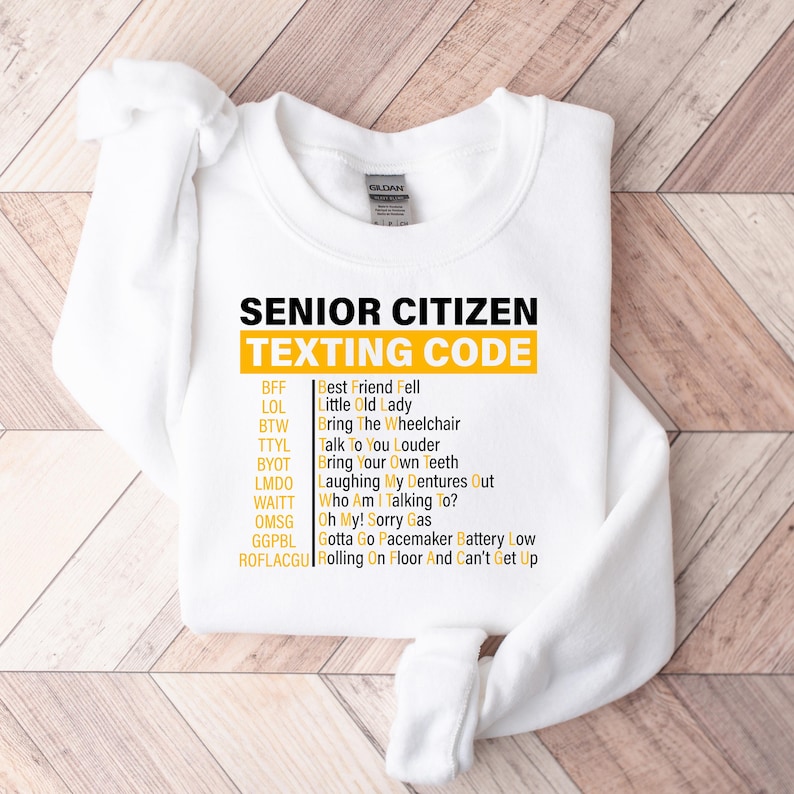 May include: White sweatshirt with a yellow graphic that says "Senior Citizen Texting Code" and lists common texting abbreviations and their meanings.