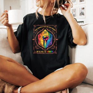 May include: Black t-shirt with a colourful graphic of a D20 die, a rainbow fist, and the text "WHEN SOMEONE ATTACKS ONE PARTY MEMBER WE ALL ROLL FOR INITIATIVE". A casual, comfortable garment.