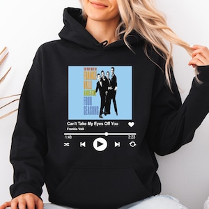 May include: Black hoodie featuring a graphic of a music player interface with the text "Can't Take My Eyes Off You" by Frankie Valli and The Four Seasons. The design includes a light blue background with a photo of the band.