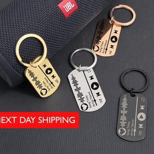 May include: Keychains in gold, silver, rose gold, and black, each featuring a music-themed design with a sound wave, play buttons, and text. The text on the keychains reads "Song Titles" and "Artist Name".