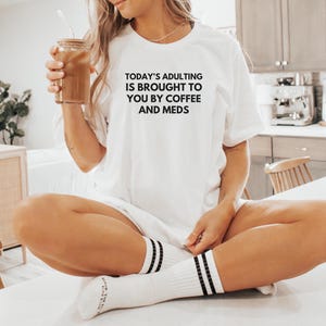 L&#39;età adulta di oggi vi viene offerta da T-shirt Coffee and Meds, maglietta divertente sulla terapia della salute mentale, maglietta contro l&#39;ansia, consapevolezza della salute mentale
