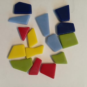 Puede incluir: Surtido de azulejos de mosaico de vidrio de colores en varias formas y tamaños, incluyendo azul, amarillo, verde y rojo.
