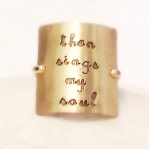 May include: A gold-toned ring with the words "then sings my soul" engraved on the band.