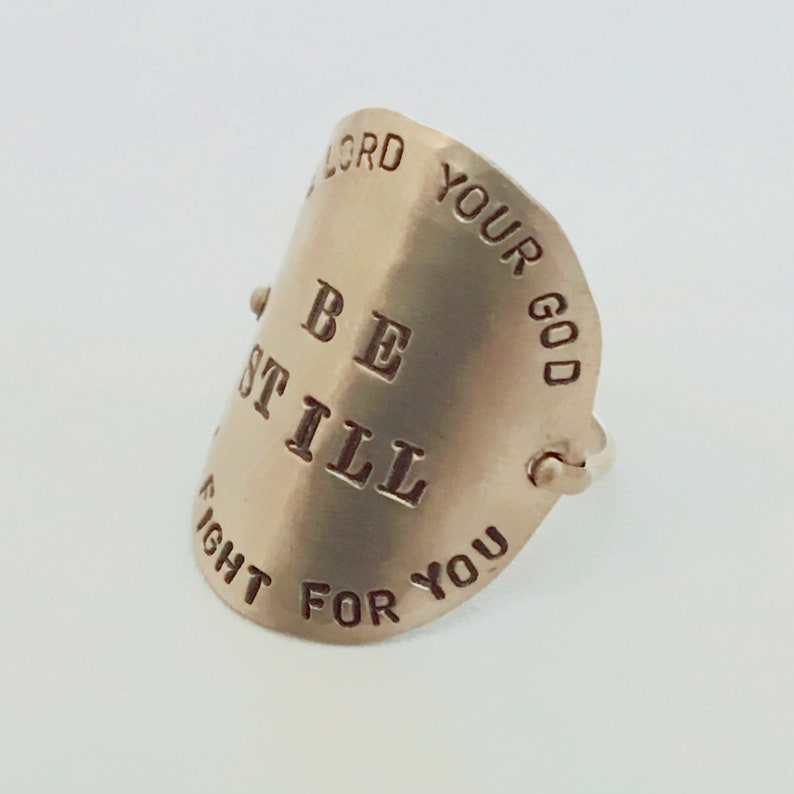 May include: A silver ring with the words "Be Still" and "Your God Will Fight For You" engraved on it.