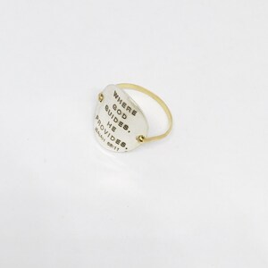 Puede incluir: Un anillo de plata con una banda de oro y un dije ovalado de plata que dice "Where God Guides, He Provides. Isaiah 58:11"