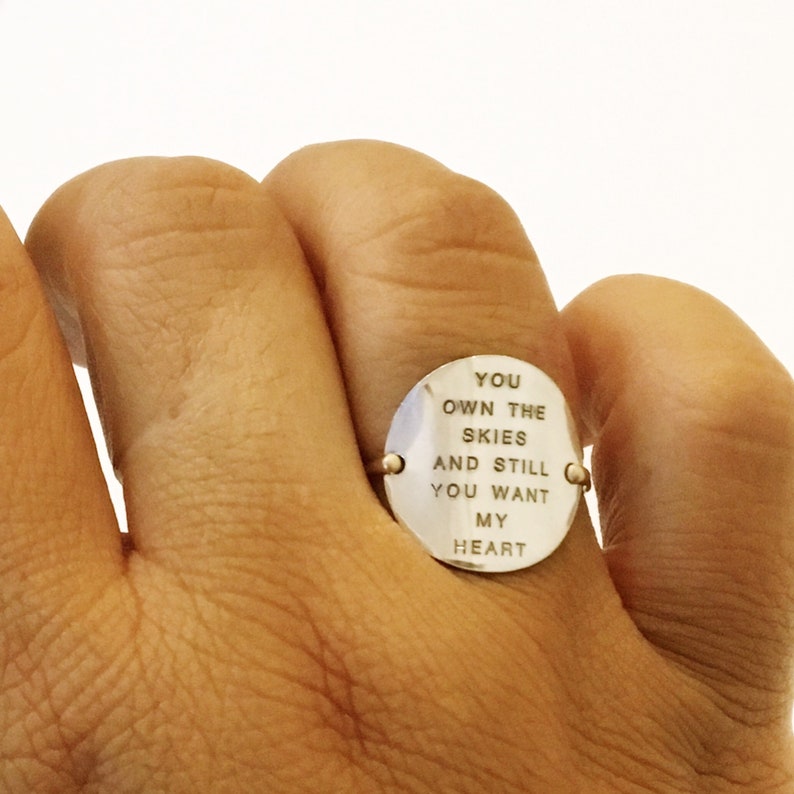 Pu&ograve; includere: Un anello d'argento con un disco rotondo inciso che recita "You own the skies and still you want my heart".