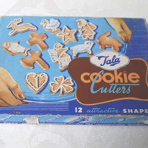 Puede incluir: Una caja azul y marr&oacute;n con el texto "Tala Cookie Cutters" y "12 formas atractivas". La caja contiene 12 cortadores de galletas en varias formas, incluyendo un pez, una cruz, un coraz&oacute;n, un tr&eacute;bol de cuatro hojas, una estrella, un cordero, un conejo, un p&aacute;jaro y un reno.
