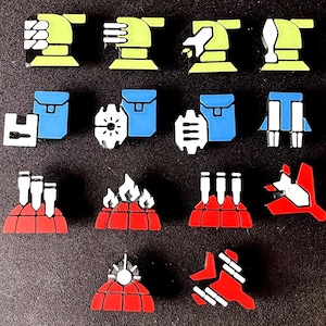 Pode incluir: Uma coleção de alfinetes coloridos em forma geométrica. Os alfinetes apresentam vários designs, incluindo mãos estilizadas, mochilas e estruturas com chaminés ou chamas. A paleta de cores inclui amarelo, azul, vermelho, branco e preto.