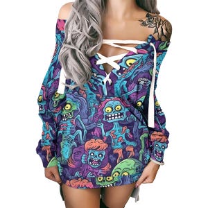 May include: A long-sleeved, off-the-shoulder dress with a colourful zombie cartoon print in blue, purple, green, and yellow. The dress has a lace-up neckline and long sleeves.