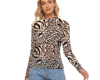 Op de afbeelding: Een top met lange mouwen en een opstaande kraag met een beige en zwarte dierenprint. De top wordt gecombineerd met lichtblauwe spijkerbroekshorts. Het patroon van de top lijkt op een zebra- of tijgerprint.