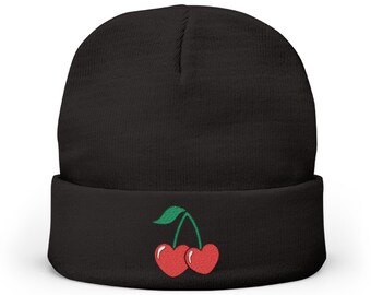 May include: Black beanie hat with a red cherry embroidery design. The cherries have a green stem and leaves. The hat is made of a soft, knitted material.