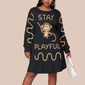 May include: Black long-sleeve dress with a crew neck featuring a cartoon monkey holding a rope. The words "STAY PLAYFUL" are printed in gold, along with rope-like designs. The dress is knee-length.